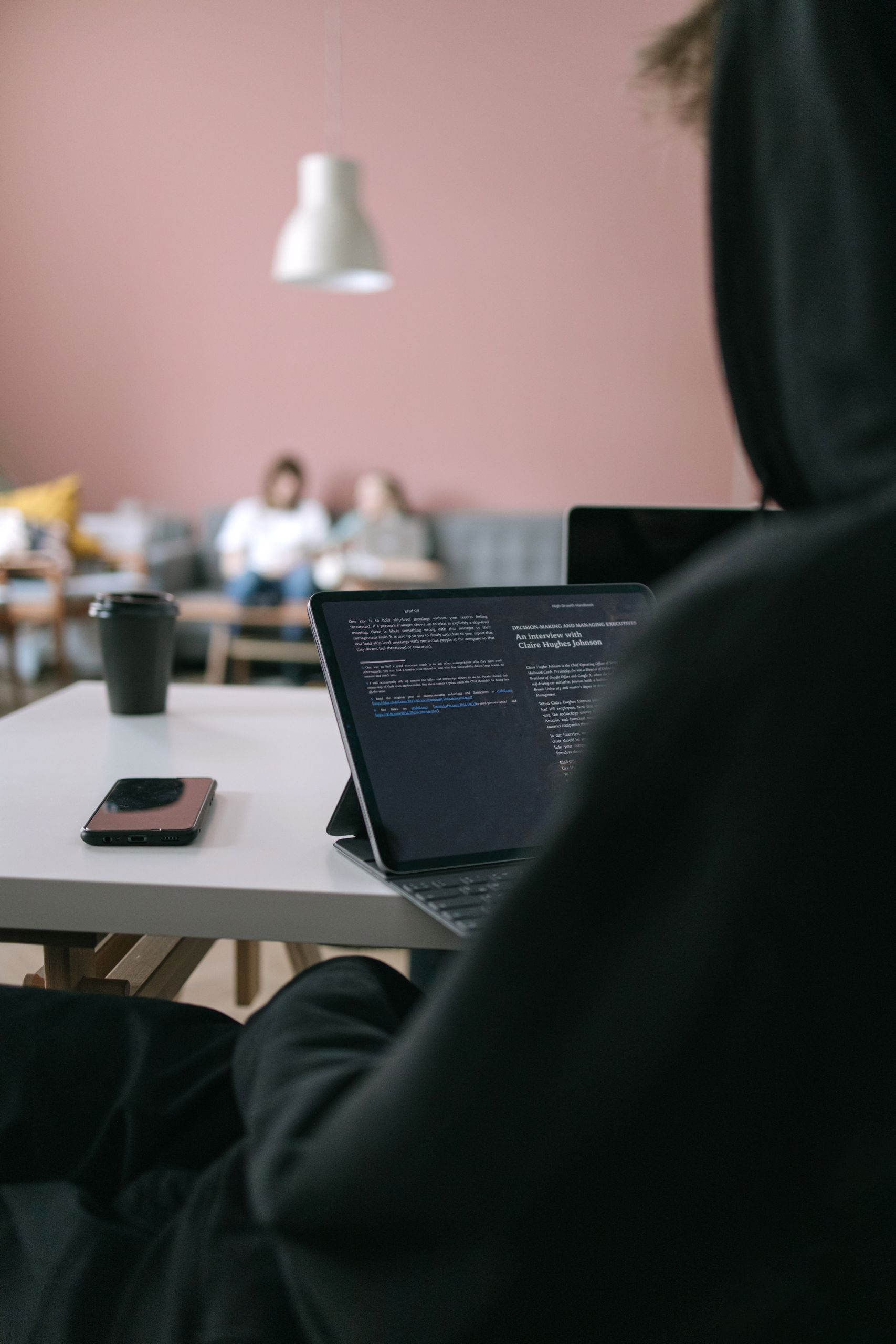 Young professional focused on laptop screen in modern workspace with casual ambiance.